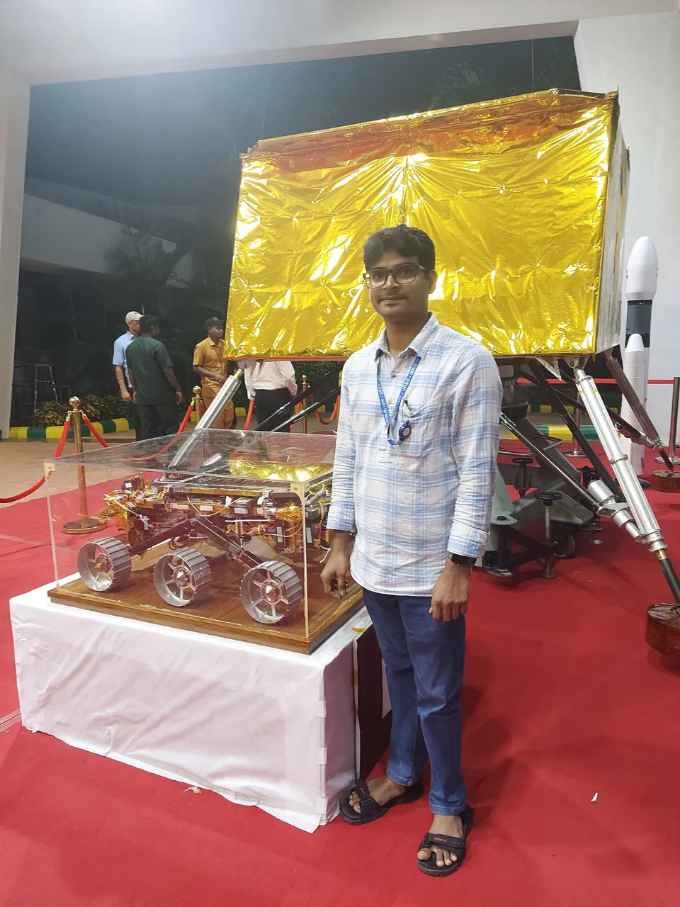 Krishna Kummari standing beside a gold-foiled lander model and a small rover model in a glass case.