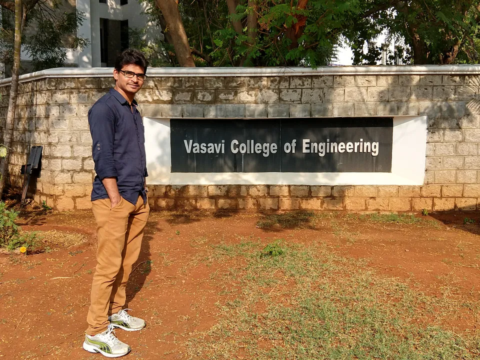 Krishna Kummari standing beside a stone wall with a sign reading Vasavi College of Engineering.