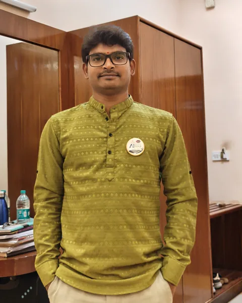 Krishna Kummari standing in front of a wooden wardrobe, wearing an olive-green kurta.